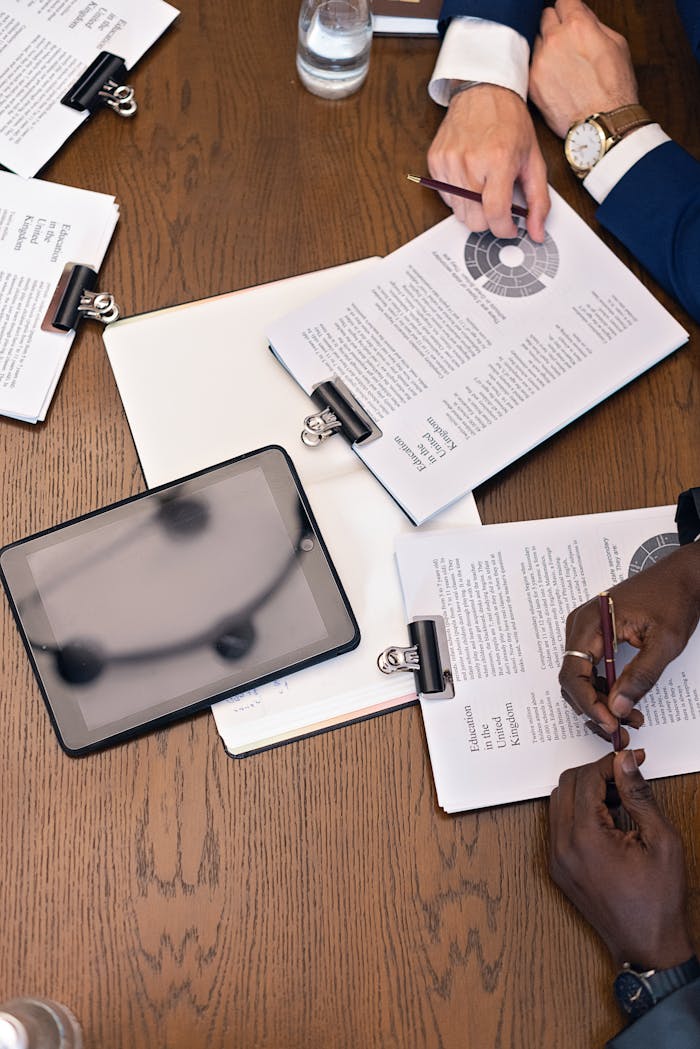 The Art of Drawing Readers In: Your attractive post title goes here Top view of a business meeting with hands, tablets, and documents on a table.